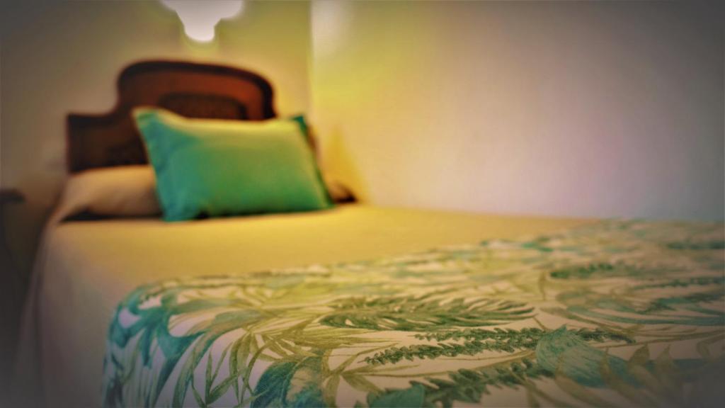 a bedroom with a bed with a green pillow at Hotel Ayamontino in Punta Umbría
