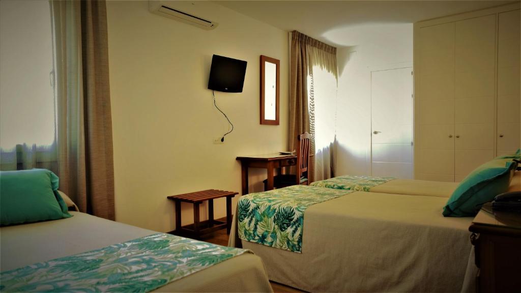 a room with two beds and a tv on the wall at Hotel Ayamontino in Punta Umbría
