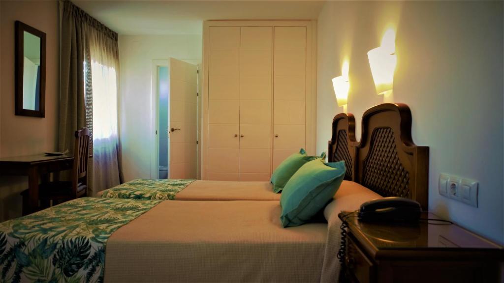 a bedroom with two beds and a table with a lamp at Hotel Ayamontino in Punta Umbría