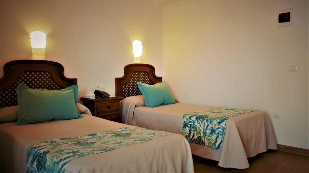 a hotel room with two beds and two lamps at Hotel Ayamontino in Punta Umbría