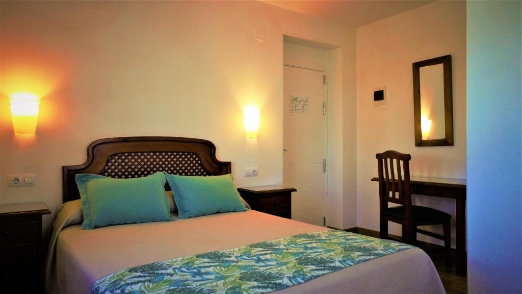 a bedroom with a bed and a desk and a chair at Hotel Ayamontino in Punta Umbría