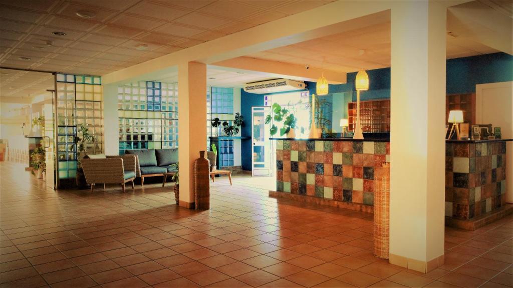 eine Lobby eines Gebäudes mit einem Wartebereich mit Tischen und Stühlen in der Unterkunft Hotel Ayamontino in Punta Umbría