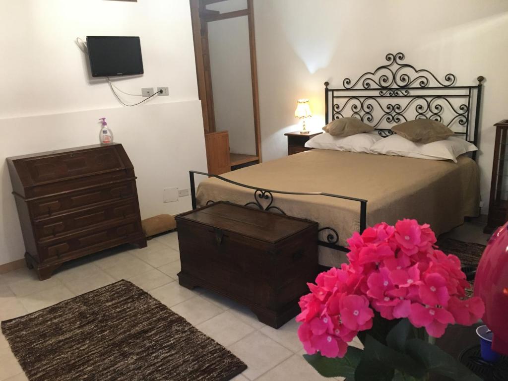 a bedroom with a bed and a dresser and pink flowers at Affittacamere Mirella in Gubbio