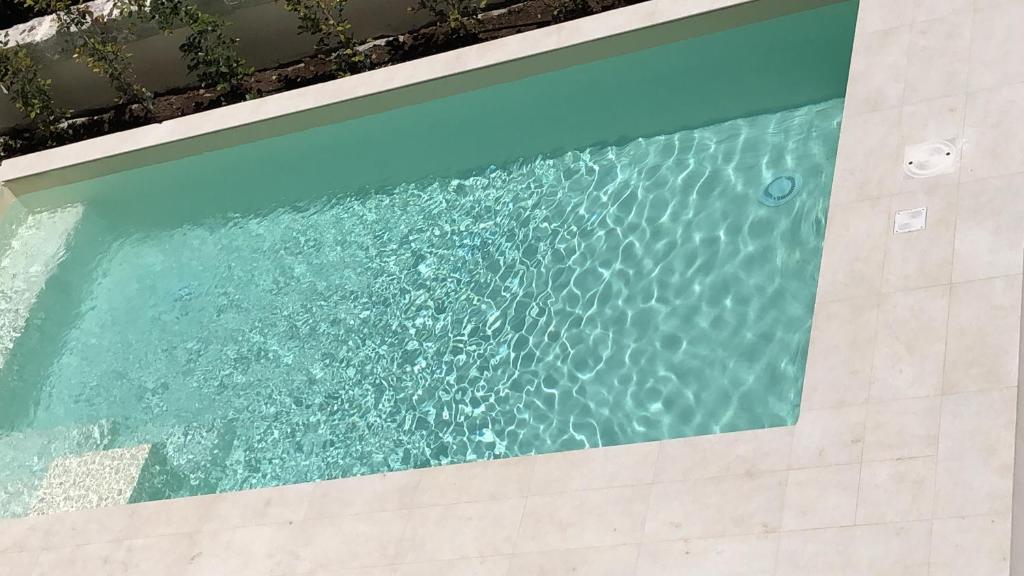 a swimming pool with blue water in a building at Carlo V - con piscina e giardino privati in Lecce
