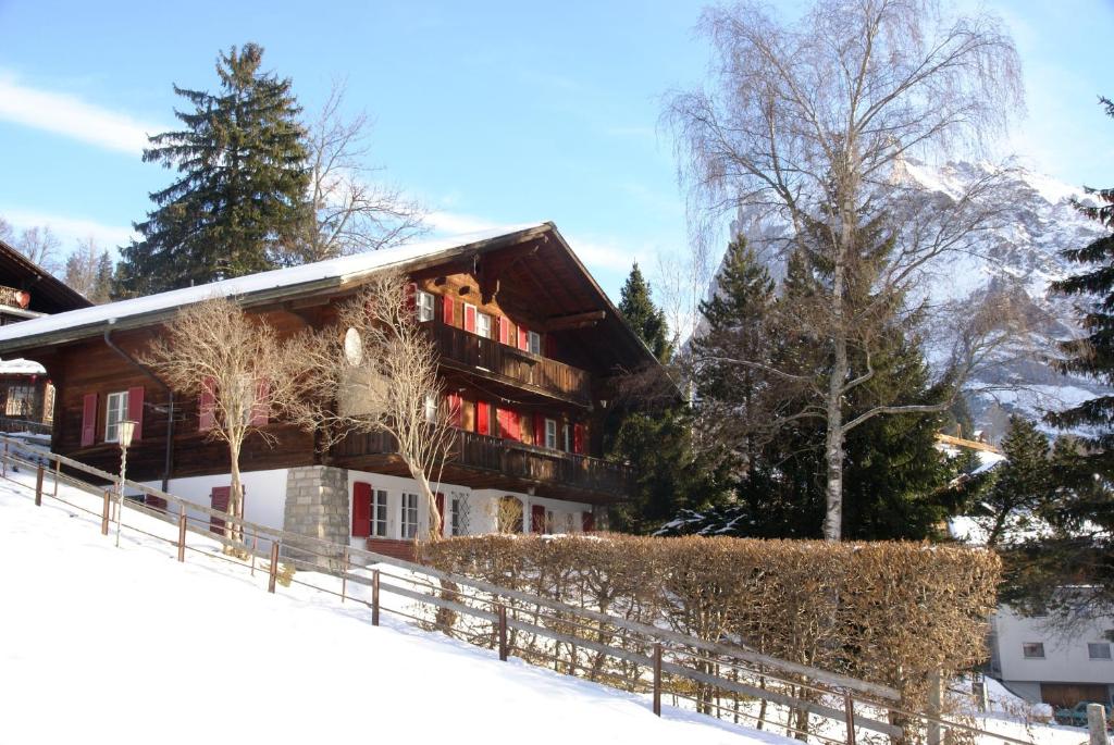 ein Haus im Schnee mit einem Zaun in der Unterkunft Chalet Grünegg in Grindelwald