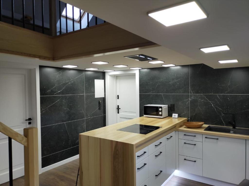 eine Küche mit weißen Schränken und einer schwarzen Wand in der Unterkunft VIP Apartament Sosnówka in Sosnowka