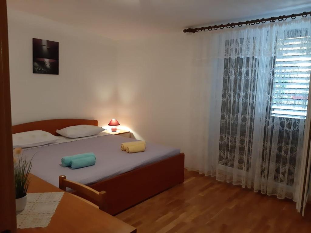 una camera con letto, tavolo e finestra di Apartmani Marija a Grebaštica