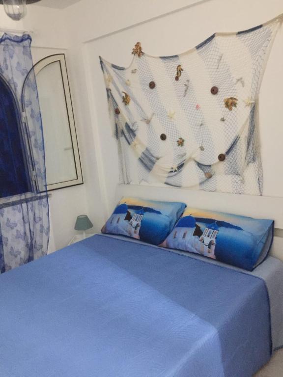 a bedroom with a blue bed with blue pillows at the goat on the beach in Scilla