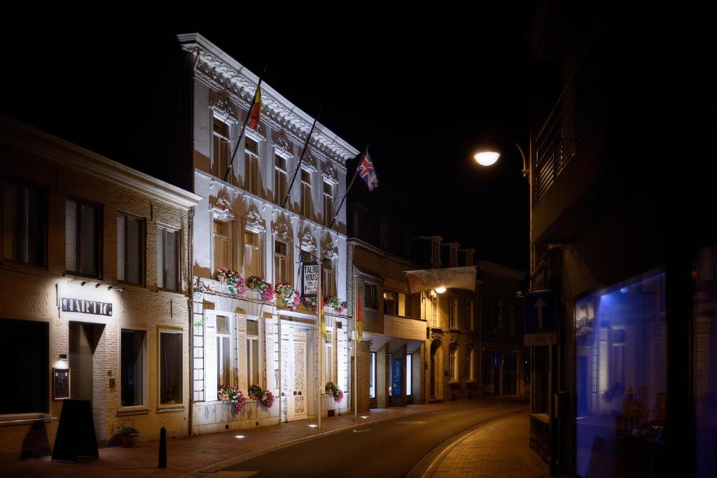 un edificio iluminado en una calle por la noche en Talbot House, en Poperinge