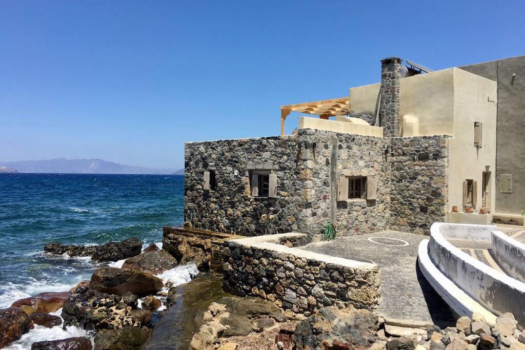 a stone building on the shore of the ocean at Poseidon House in Mandrakion