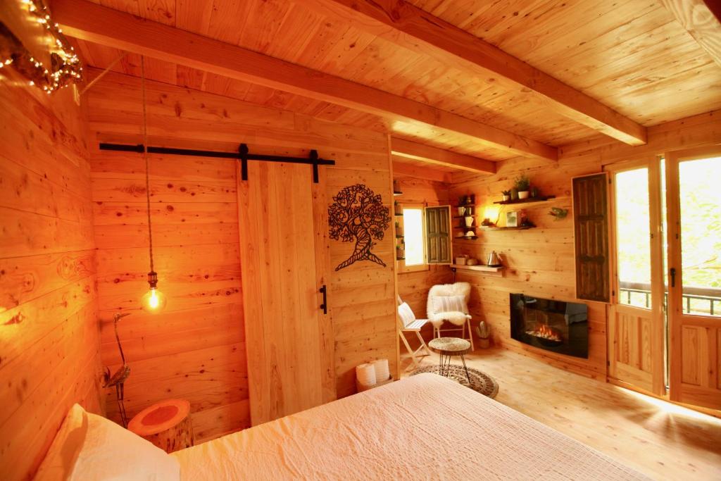 una camera da letto in una baita di tronchi con letto e camino di NatureTreeHouse Casa sobre los árboles a Blanes