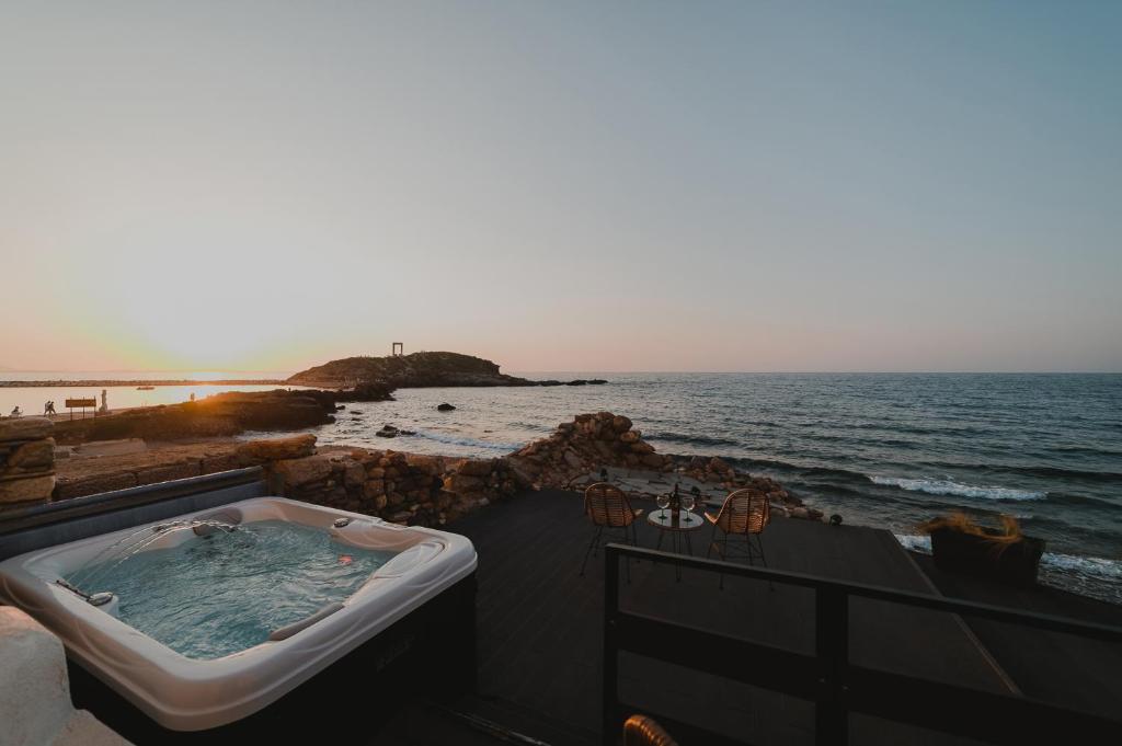 e balcone con vasca e vista sull'oceano. di Portara Seaside Luxury Suites a Naxos Chora