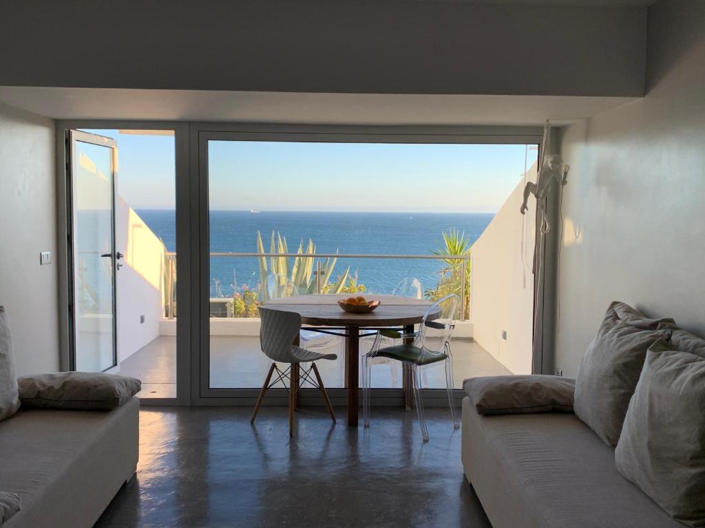 a living room with a table and a view of the ocean at Refúgio da Falésia in Sesimbra