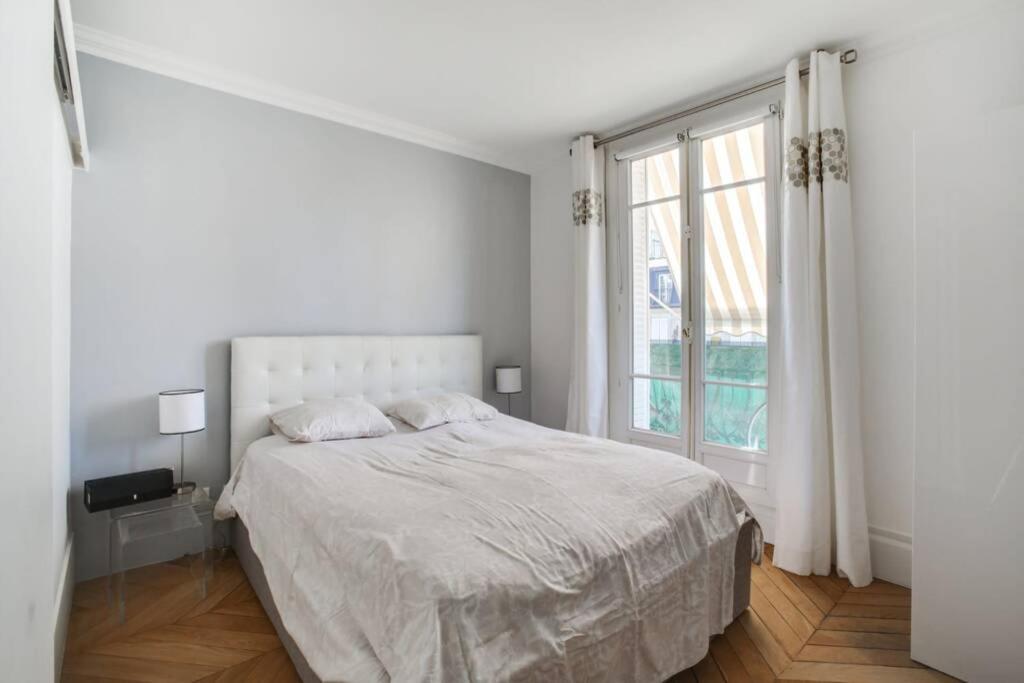 a white bedroom with a bed and a window at Trocadéro in Paris