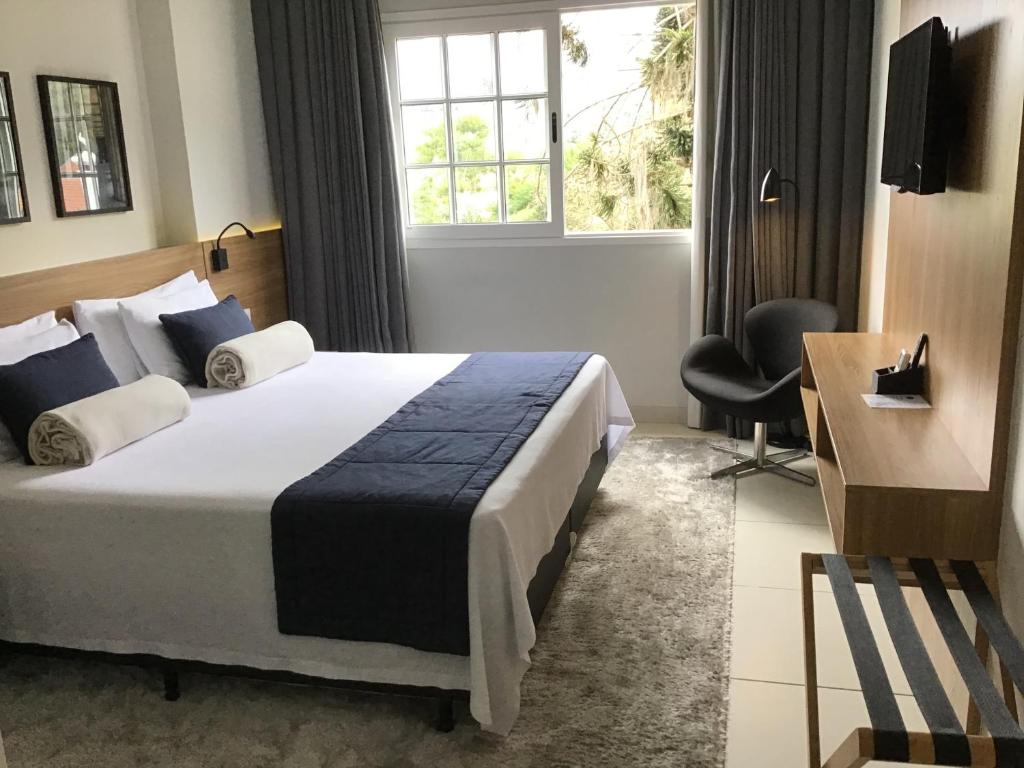 een hotelkamer met een bed, een bureau en een raam bij Flat Itaipava - Granja Brasil in Itaipava