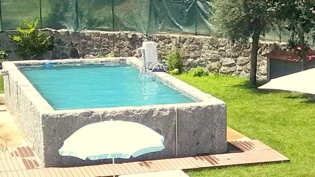 a swimming pool with a fountain in a yard at Casa da Lagiela rural senses in Fafe