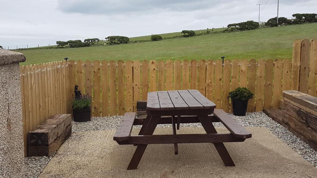 a picnic table in front of a wooden fence at Tornabodagh House in Ballycastle