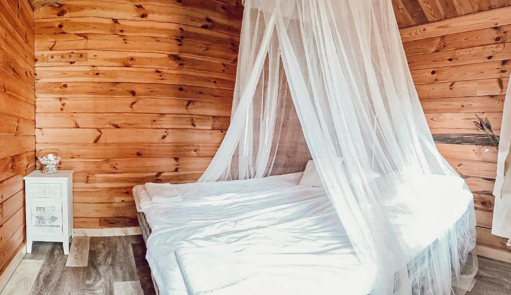 Cama en habitación de madera con mosquitera en Pruuli Puhkeküla, en Nurme