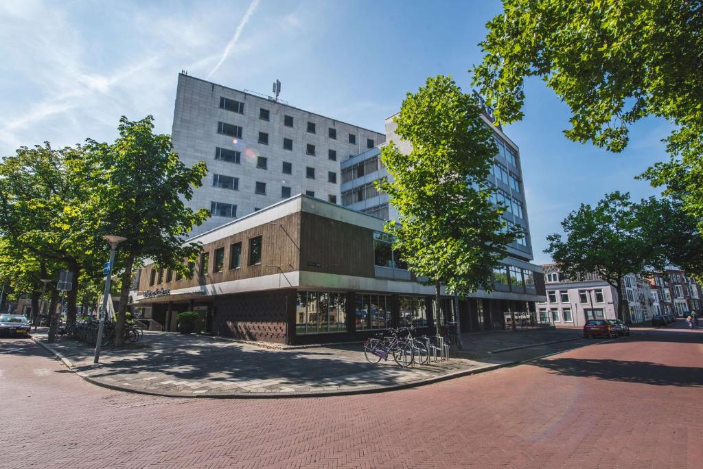 a large building on a city street with trees at Flonk Hotel Groningen Centre, BW Signature Collection voorheen Best Western Hotel Groningen Centre in Groningen