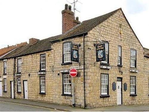 un grand bâtiment en briques avec deux réveils dans l'établissement Queen in the West, à Lincoln