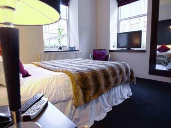 Una habitación de hotel con una cama con una manta. en Rab Ha's en Glasgow