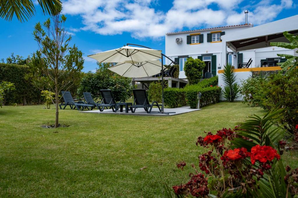 a patio with chairs and an umbrella in front of a house at Casa da Quinta in Vila Franca do Campo