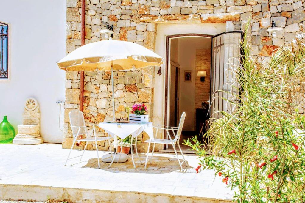 een tafel en stoelen met een parasol op een patio bij Casale Conte Dell'Anna in Porto Cesareo
