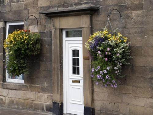 ein Gebäude mit einer weißen Tür mit Blumen darauf in der Unterkunft The Reading Rooms in Haydon Bridge