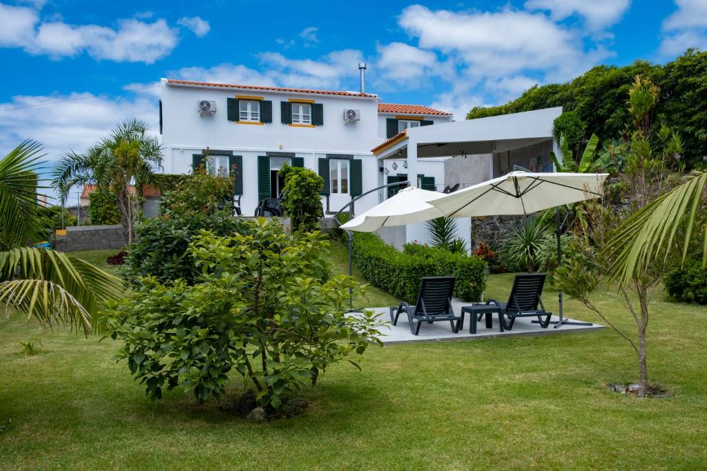 a white house with two chairs and an umbrella at Casa da Quinta in Vila Franca do Campo