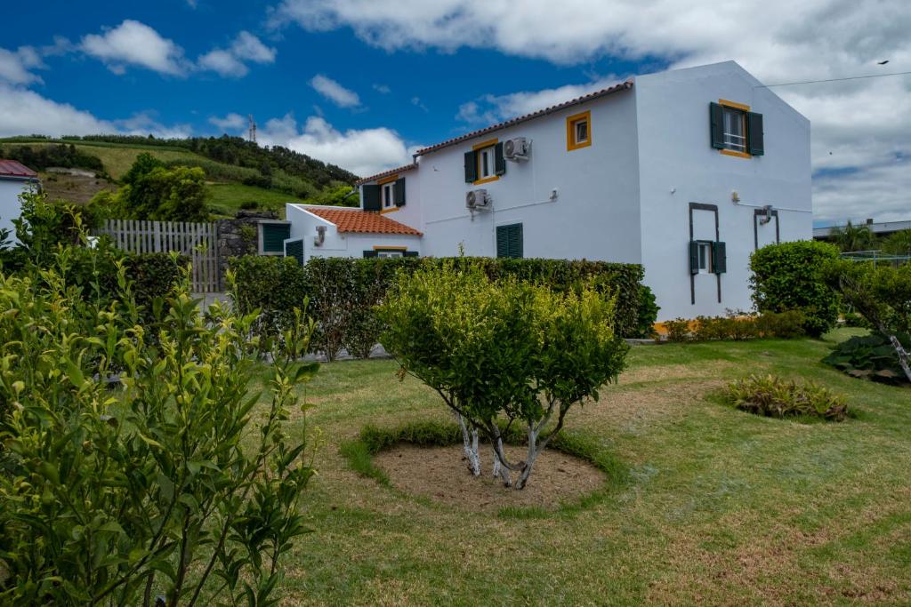 a white house with a garden in front of it at Casa da Quinta in Vila Franca do Campo