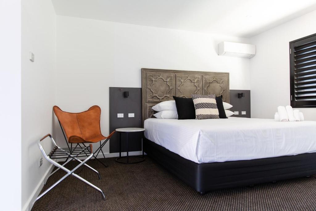 Un dormitorio con una cama grande y una silla. en Fountain View Motel, en Dubbo