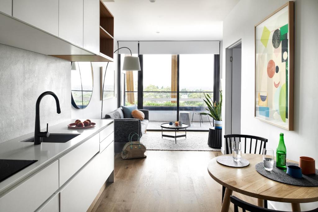 a kitchen with a table and a living room at Punthill Ivanhoe in Melbourne