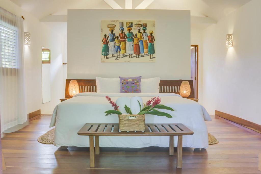 1 dormitorio con cama blanca y mesa en Pousada Calypso, en Trancoso