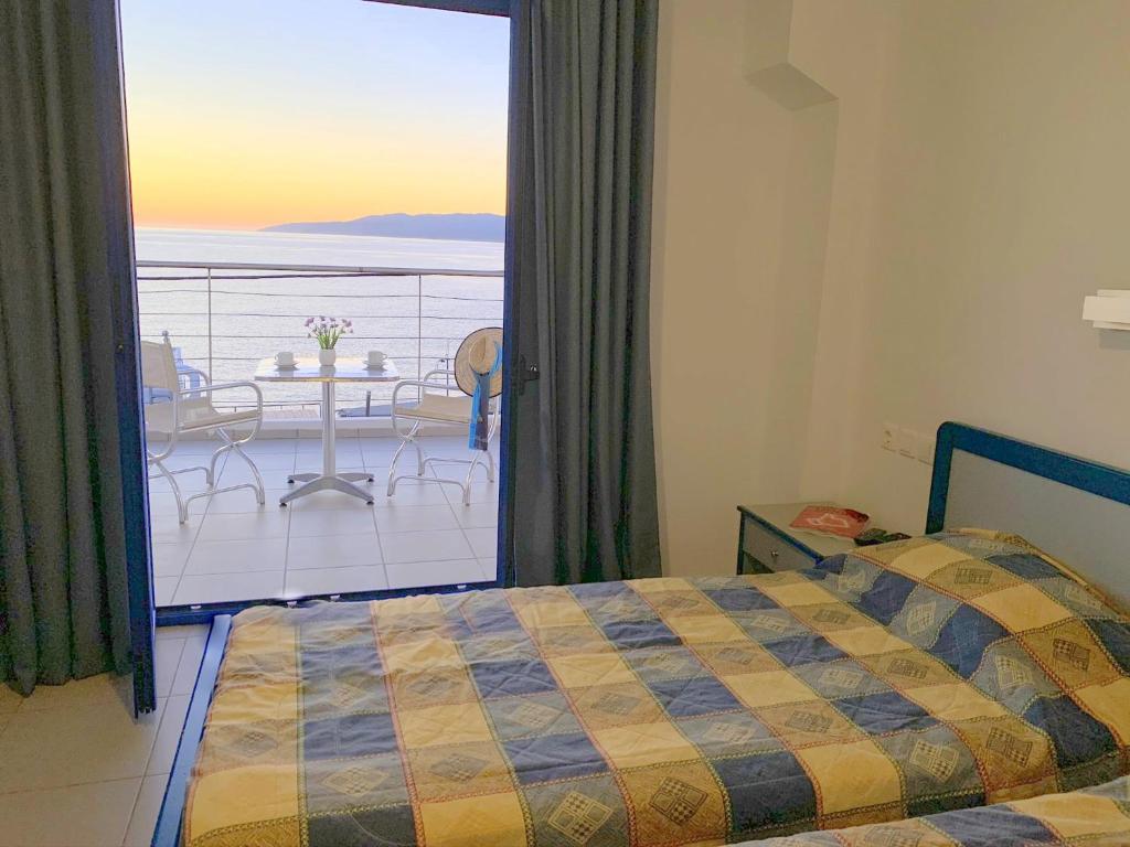 a bedroom with a bed and a view of a balcony at Kassavetis Center - Hotel Studios & Apartments in Hersonissos