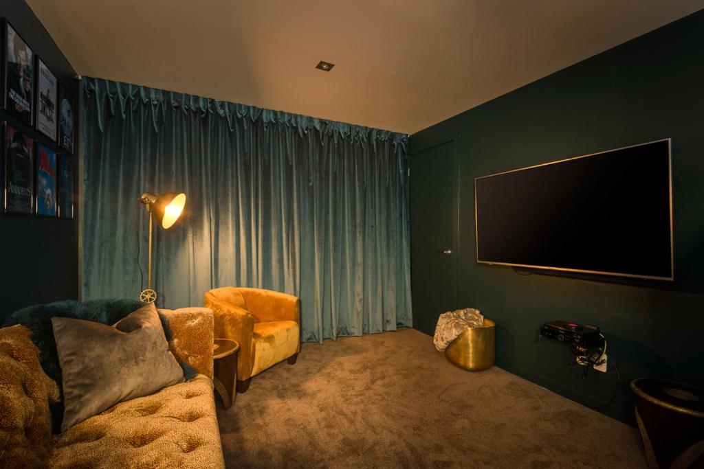 sala de estar con sofá y TV de pantalla plana en Love Akaroa Retreat, en Akaroa