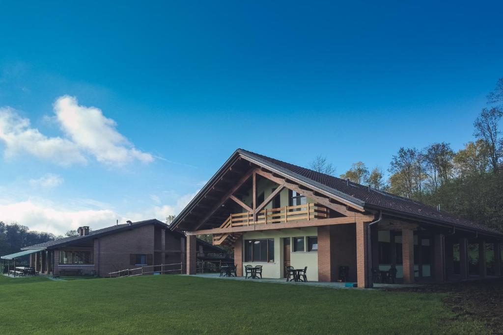 a large house with a gambrel roof and a grass field at Agriturismo Altana Del Motto Rosso in Gattico