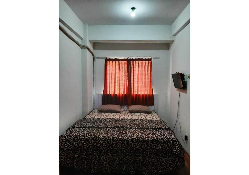ein kleines Schlafzimmer mit einem Bett mit einem roten Vorhang in der Unterkunft Royal Property in Jakarta