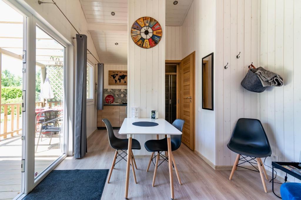 um quarto com uma mesa e cadeiras e um relógio em Les minis homes du Bugey - Eco-lodge City, un refuge en hyper centre em Ambérieu-en-Bugey