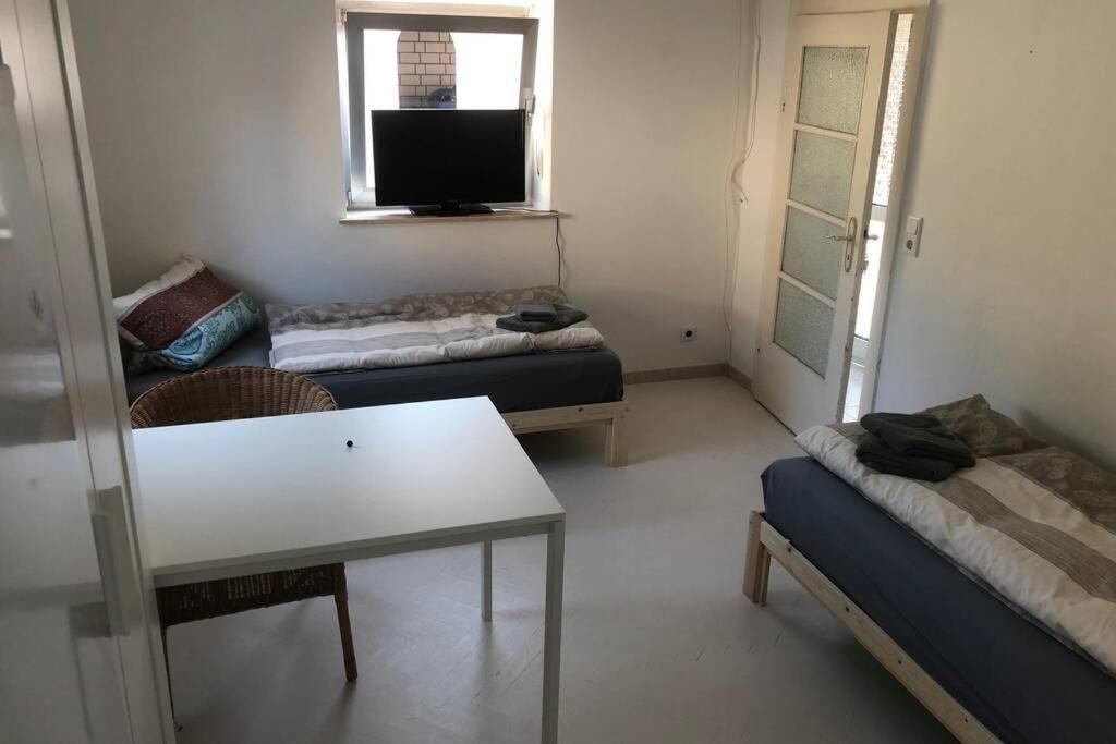 a room with two beds and a table and a tv at Sachsenhausen in Alzenau