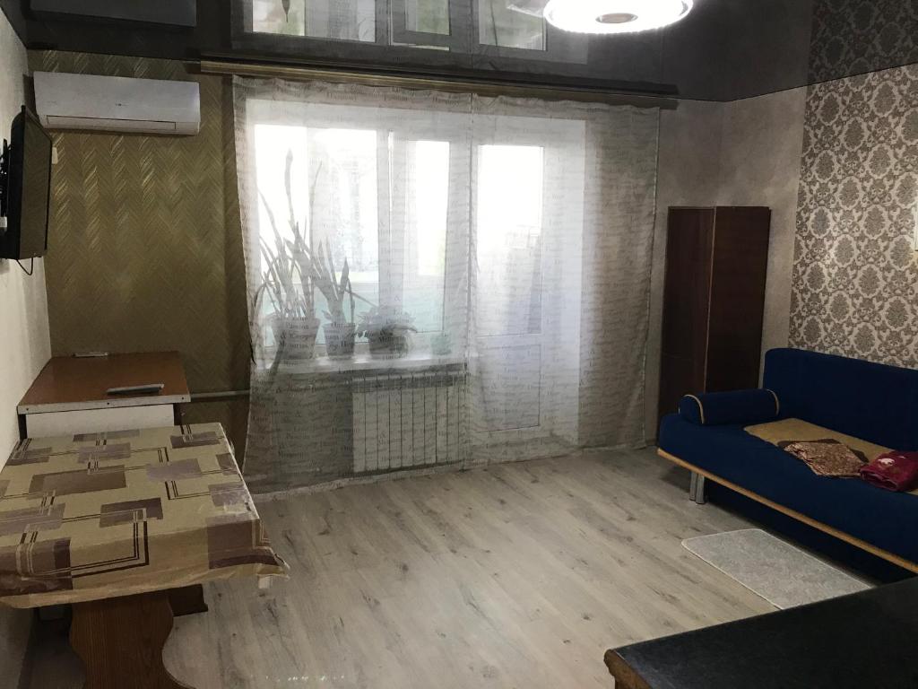 sala de estar con sofá azul y ventana en 1комнатная квартира, en Yuzhne