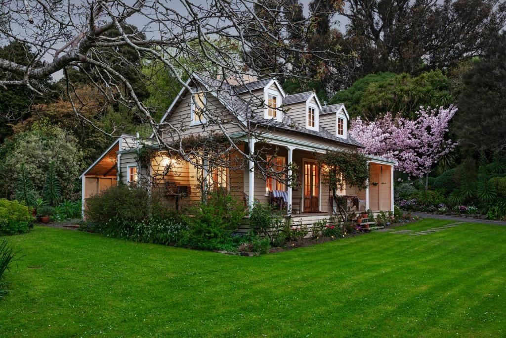 a house with a green lawn in front of it at Mill Cottage - boutique accommodation and garden in Akaroa