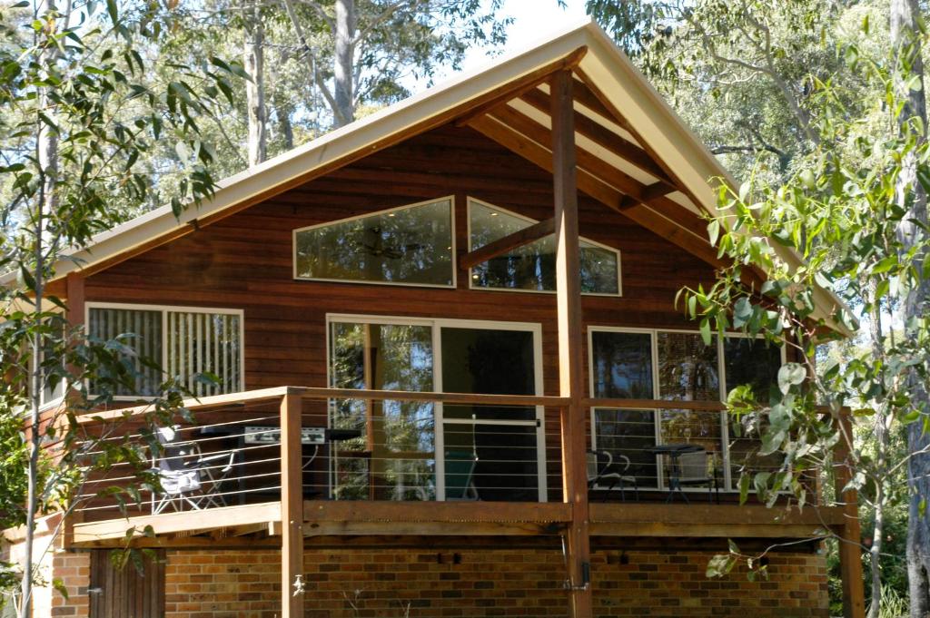 a house with a wrap around deck in the woods at Bewong River Retreat in Bewong