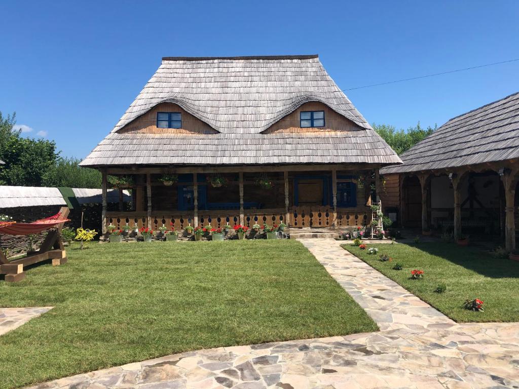 une grande maison en rondins avec une cour d'herbe dans l'établissement Casa Colț din Maramureș - Old Traditional House, à Ocna Şugatag
