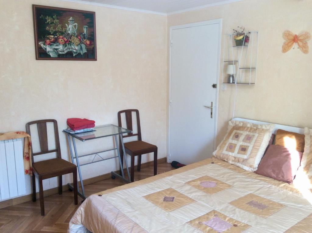 1 dormitorio con 1 cama, mesa y sillas en CHAMBRE INDEPENDANTE + SANITAIRE près centre ville en Rignac