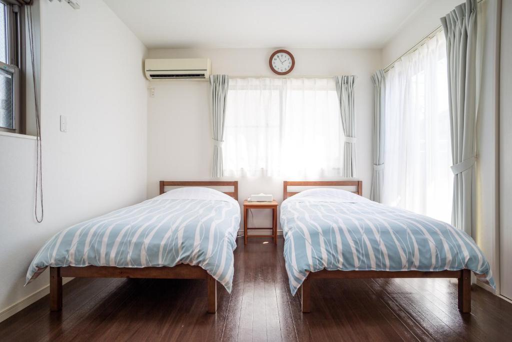 two beds in a bedroom with a clock on the window at KOSHIGOE seaside inn in Kamakura