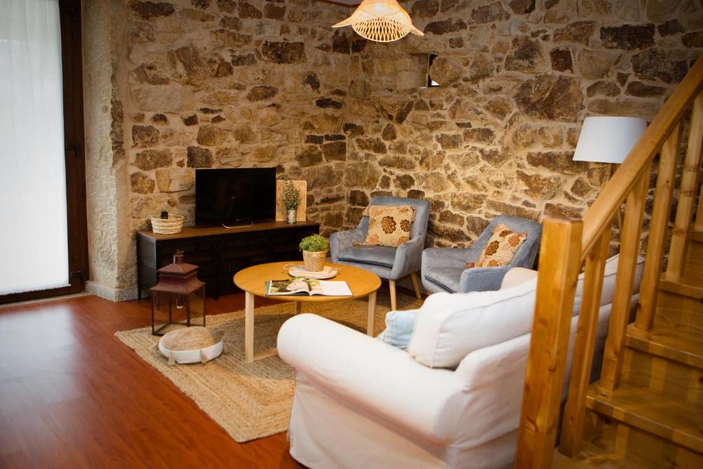 un soggiorno con divano bianco, sedie e TV di Miña Nai, Casa Rural a Lalín