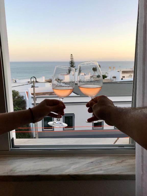 two people holding wine glasses in front of a window at Sea Light Seaview Vista Mar Apartment - Luz, Lagos in Luz