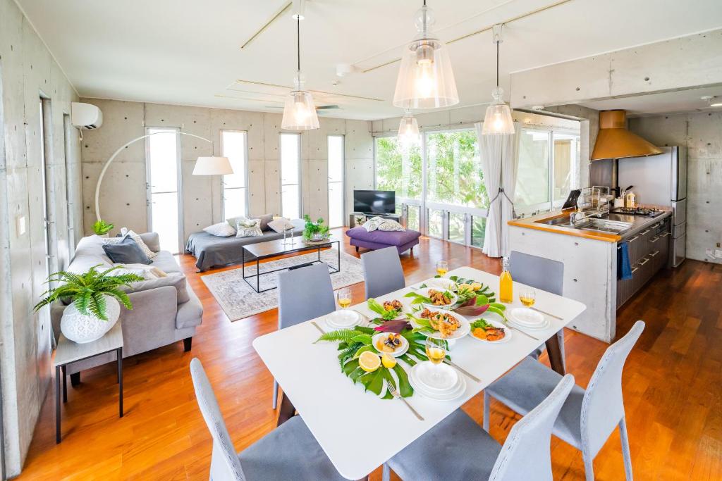 una cucina e un soggiorno con tavolo e sedie bianchi di EM Tree House a Uruma
