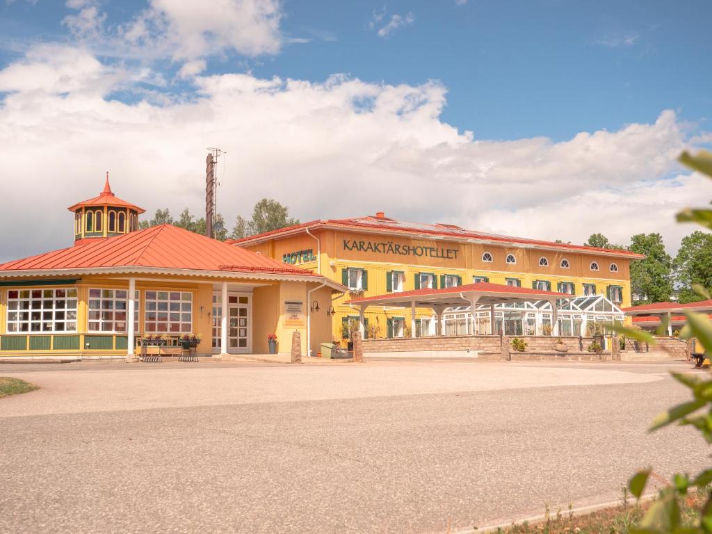 a large yellow building with a red roof at Björkbackens Karaktärshotell in Vimmerby