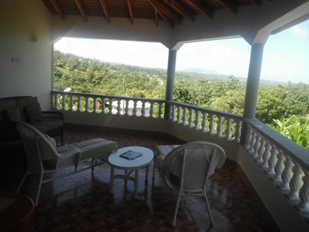 Classique International in Dominica في Marigot: شرفة مع أريكة وكراسي وطاولة